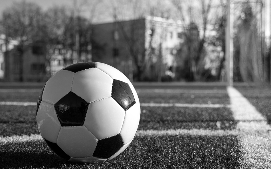 A soccer ball sits on a goal line of a field before the game starts.
