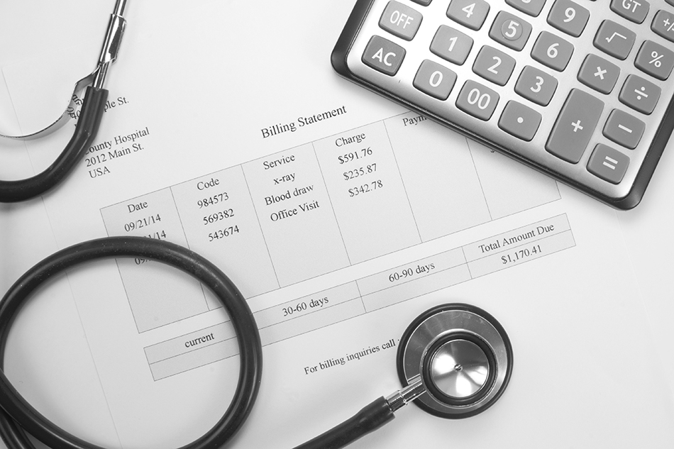 A close-up of a medical bill, stethoscope, and calculator. 