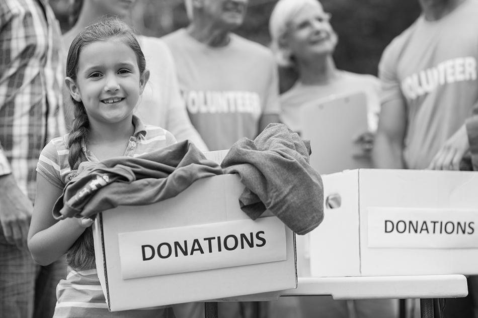 A young girl helps older volunteers collect clothing donations at an event covered by Accident Medical protection. 